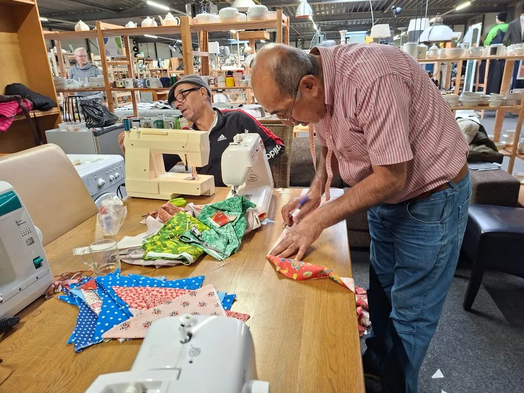 Twee mannen zijn samen aan het naaien in het naaiatelier in Baarn