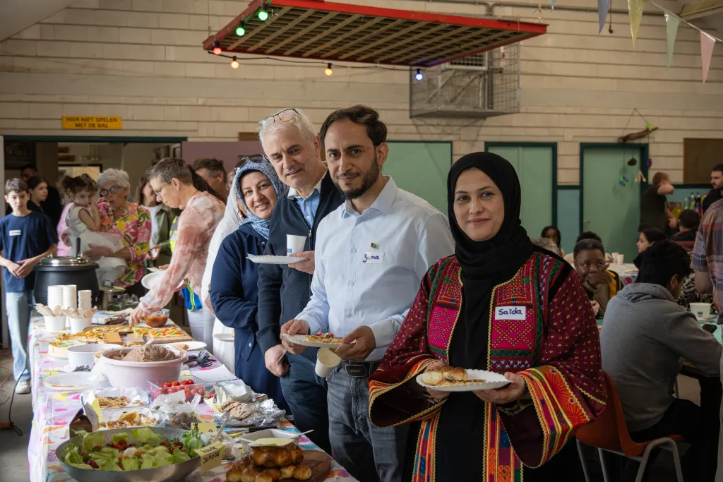 Mannen en vrouwen staan bij het buffet tijdens Samen Eten event in Boekel